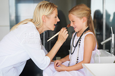 Buy stock photo Little girl having make-up applied by her mother with a smile