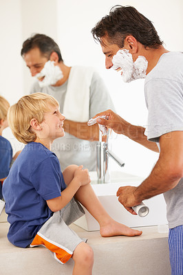 Buy stock photo A young boy talking to his Dad while he's shaving