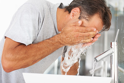 Buy stock photo Hygiene, hydration and a man washing his face in the bathroom of his home in the morning to wake up. Fresh, water and cleaning with a male person in his house to start a skincare or moisture routine