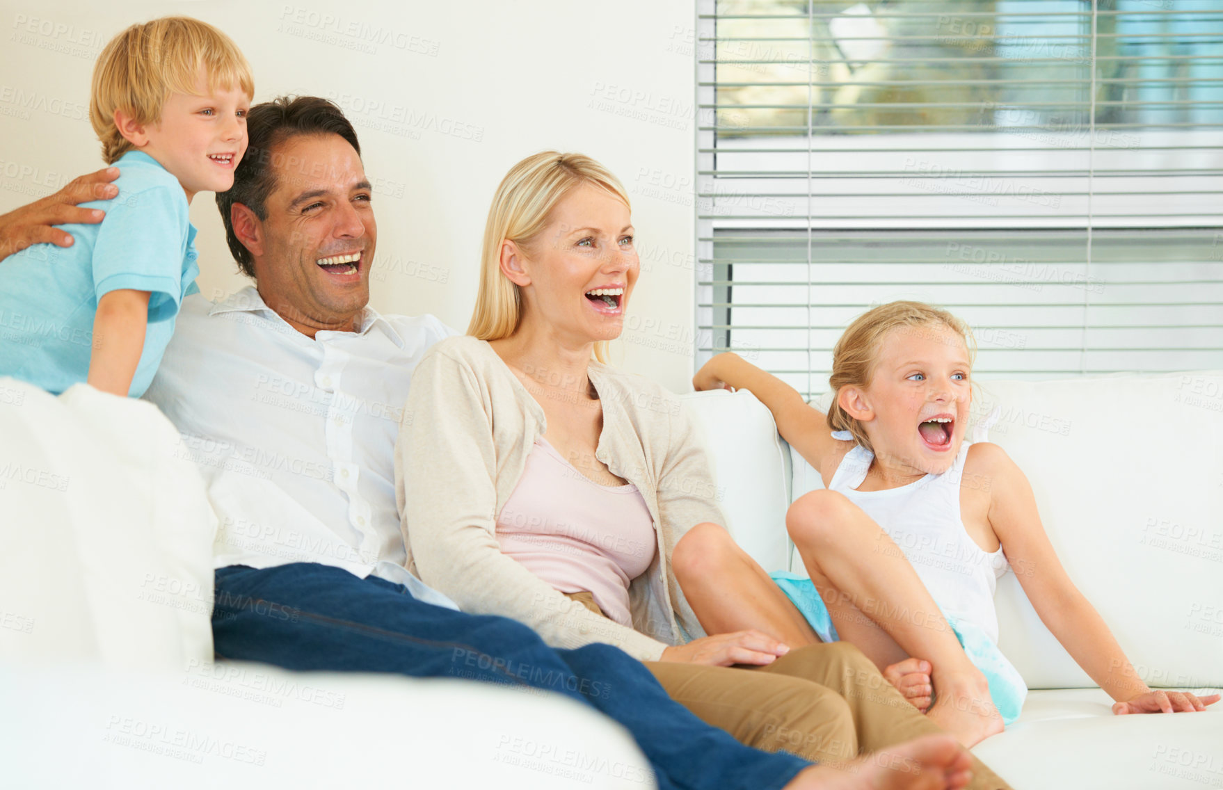 Buy stock photo A loving family of four watching a movie together in the lounge