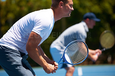 Buy stock photo Shot of two men playing a tennis match on a sunny day