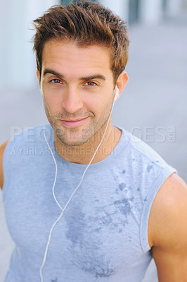 Buy stock photo Fitness, portrait and man athlete running with sweat on road for exercise, cardio or outdoor training. Active, sports and young male person with smile and earphones for music, playlist or album.