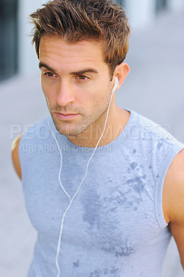 Buy stock photo Closeup of a handsome young man in a sweaty shirt listening to music on his earphones
