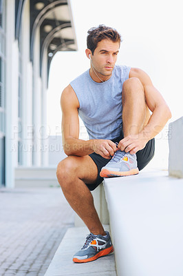 Buy stock photo Man, fitness and tying shoes getting ready for workout, exercise or outdoor training with earphones. Active male person or athlete tie shoe on concrete bench in preparation for run or cardio outside