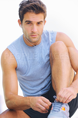 Buy stock photo Man, portrait and tying shoes with earphones in fitness for workout or exercise against a white studio background. Active male person or athlete sitting to tie shoe in preparation for cardio training