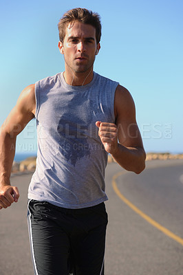 Buy stock photo Handsome young man jogging down the road