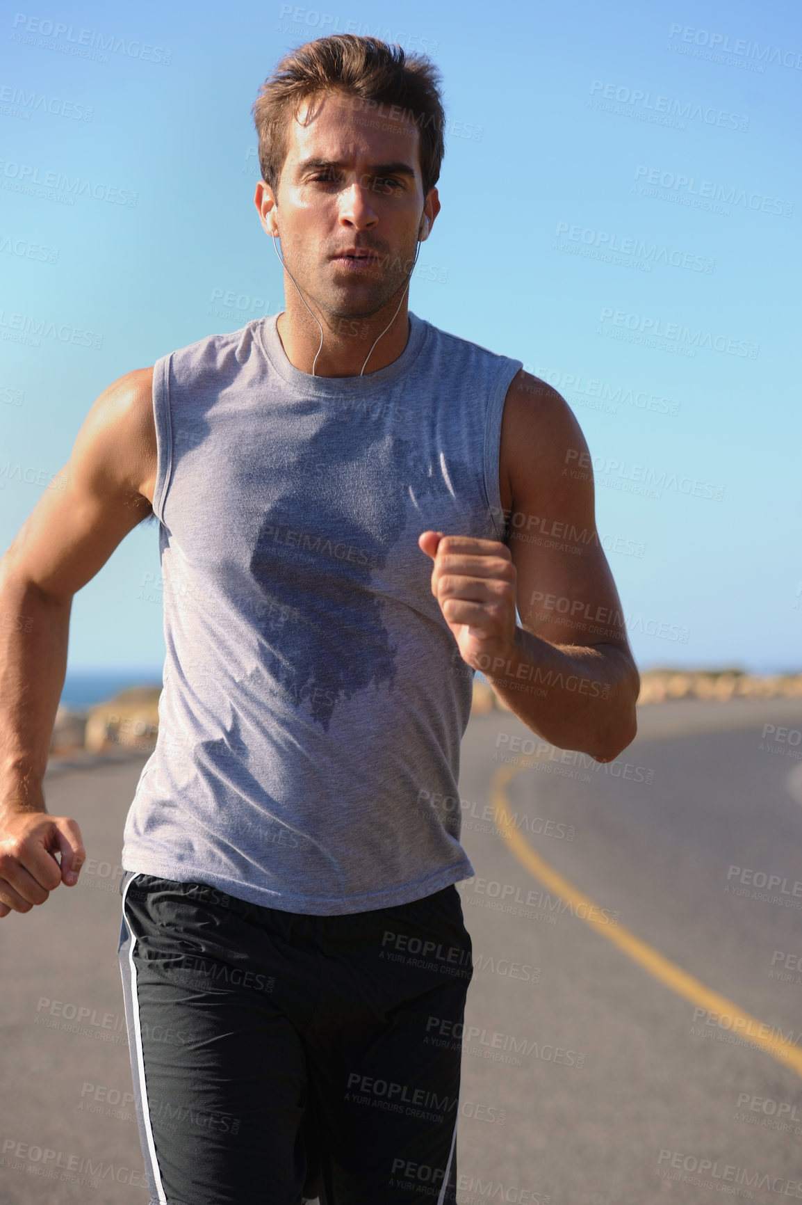 Buy stock photo Handsome young man jogging down the road