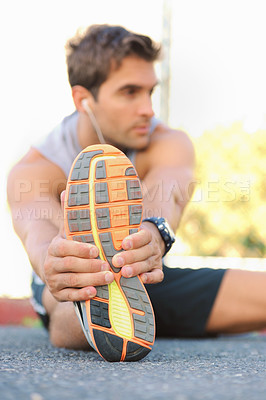 Buy stock photo Young jogger sitting and stretching while looking sideways