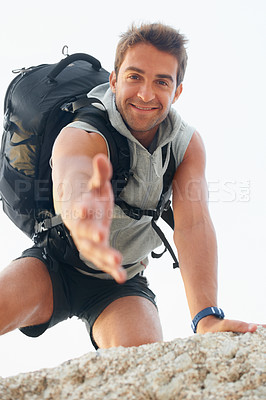 Buy stock photo Handsome young mountain climber extending his hand towards the camera