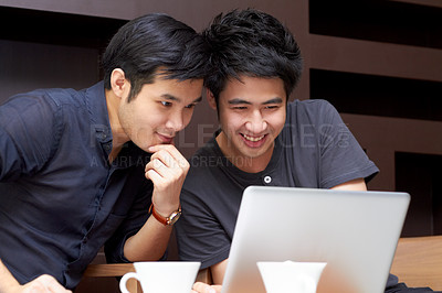 Buy stock photo Two young Asian guys surfing the web together on a laptop