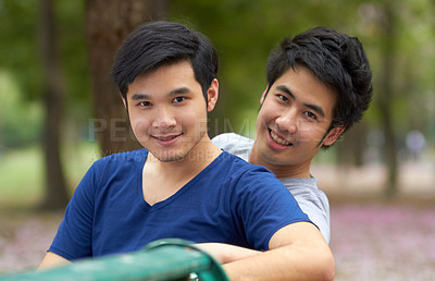 Buy stock photo Cute young gay Asian couple smiling together while sitting in the park