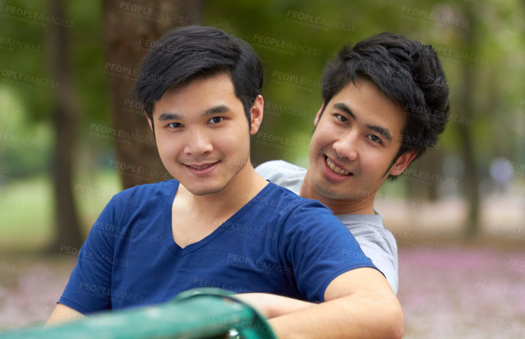 Buy stock photo Cute young gay Asian couple smiling together while sitting in the park