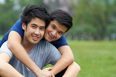 Buy stock photo Cute young gay Asian couple smiling together while sitting in the park