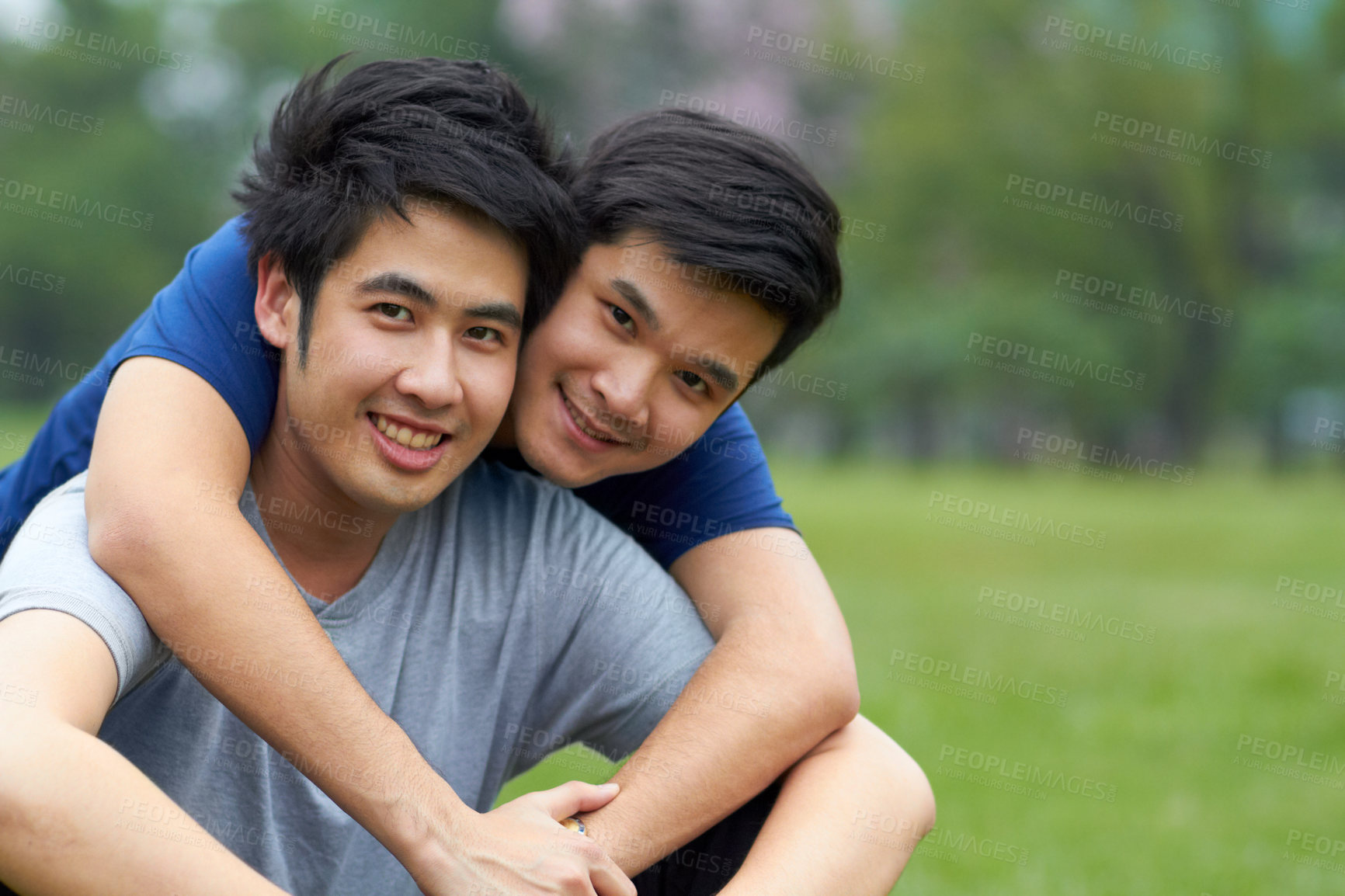 Buy stock photo Cute young gay Asian couple smiling together while sitting in the park