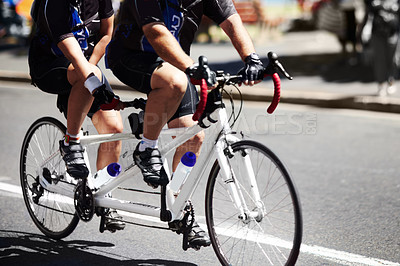 Buy stock photo A cropped shot of two people riding a tandem bicycle