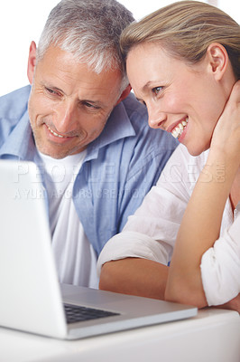 Buy stock photo A mature couple looking content as they work on their laptop at home