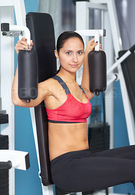 Buy stock photo Portrait of an attractive young woman using an exercise machines at the gym