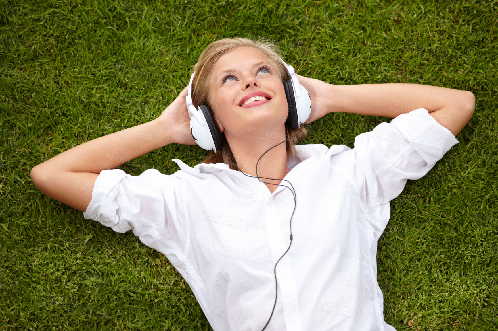 Buy stock photo High angle shot of a woman lying on a grassy field listening to musicHigh angle shot of a woman lying on a grassy field listening to music with her eyes closed