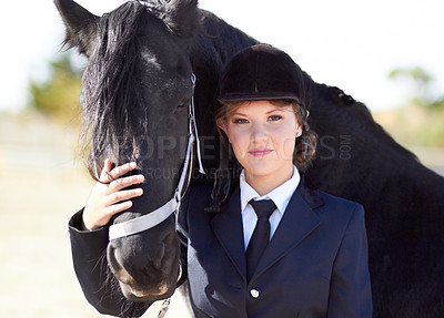 Buy stock photo Portrait of a young female rider stroking her horses face and smiling proudly at the camera