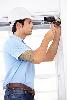 Buy stock photo Shot of a handsome young man    installing a security camera