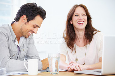 Buy stock photo Shot of a two positive-looking young design professionals sitting together and discussing something on a laptop