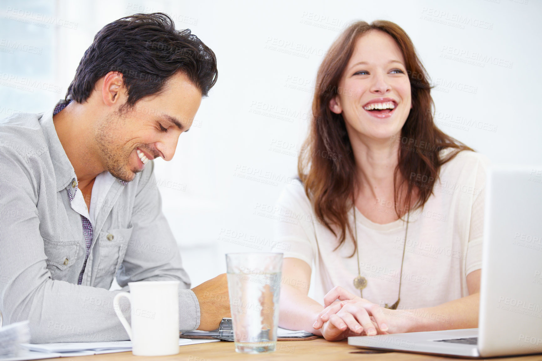 Buy stock photo Shot of a two positive-looking young design professionals sitting together and discussing something on a laptop