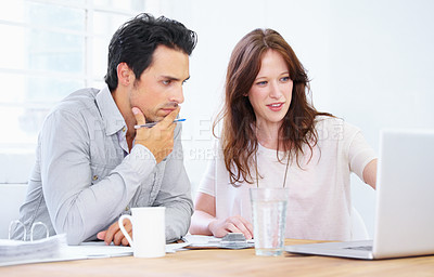 Buy stock photo Shot of a two young  professionals sitting together and discussing something on a laptop