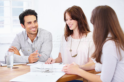 Buy stock photo Shot of a group of young design professionals sitting at a table and having a brainstorming session