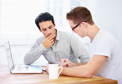 Buy stock photo Shot of two young business professionals in deep conversation over a laptop