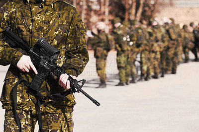 Buy stock photo A soldier standing with a rifle and his fellow soldiers in the background