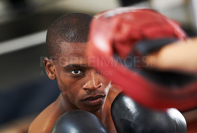 Buy stock photo A young boxer throwing a punch at his partner's sparring glove
