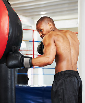 Buy stock photo An african american boxer practicing with a punching ball