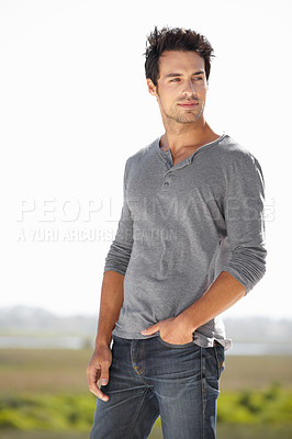 Buy stock photo A handsome young man standing outside with his hands in his pockets