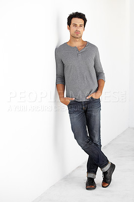 Buy stock photo Portrait of a handsome young man leaning against a wall with his hands in his pockets