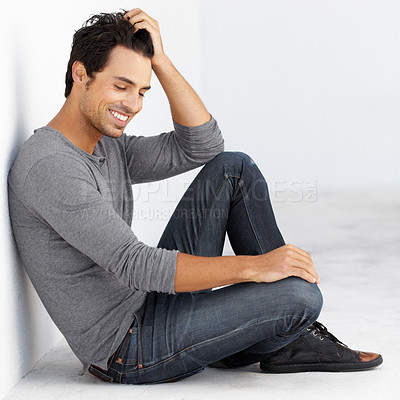 Buy stock photo A handsome young man sitting against a wall with his eye closed
