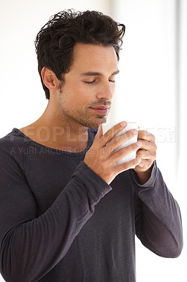 Buy stock photo A handsome young man taking in the aroma of his morning coffee