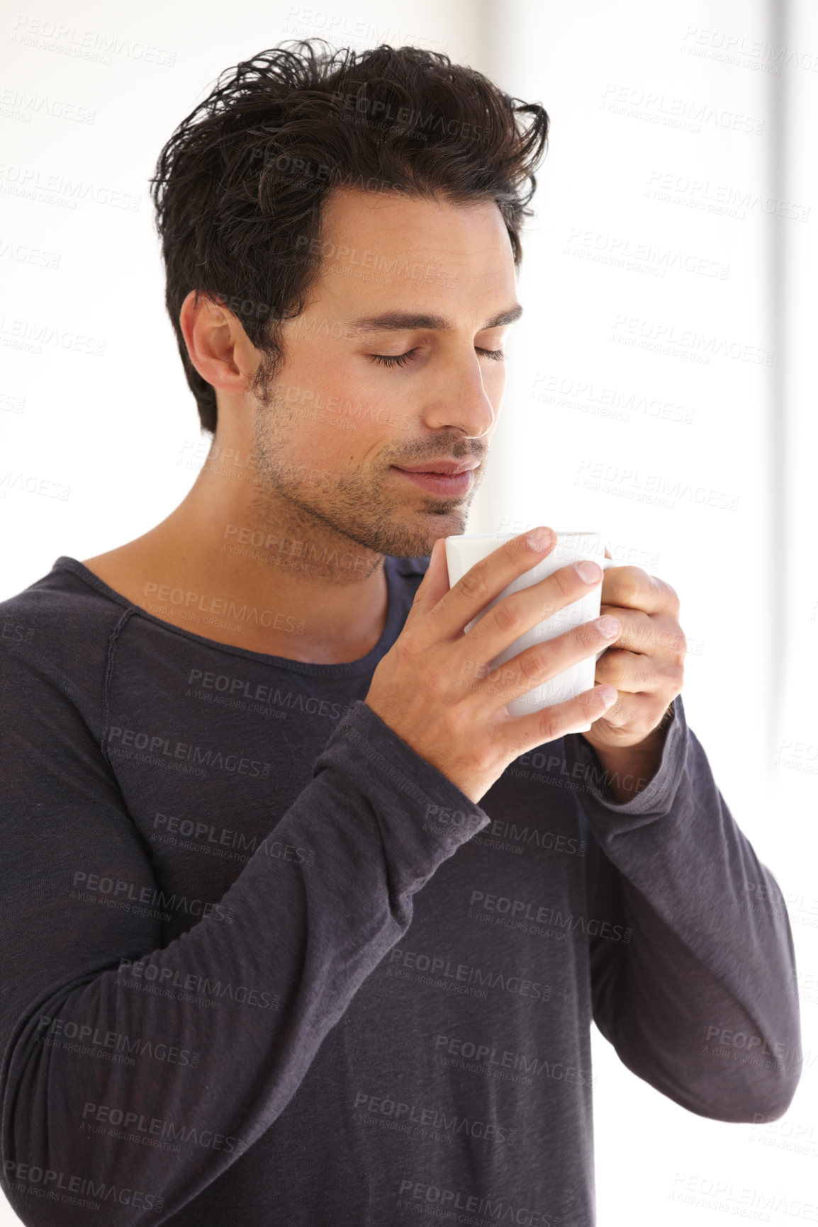 Buy stock photo A handsome young man taking in the aroma of his morning coffee