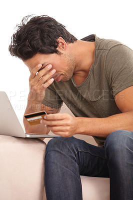 Buy stock photo A young man with his head in his hand looking upset while holding his credit card