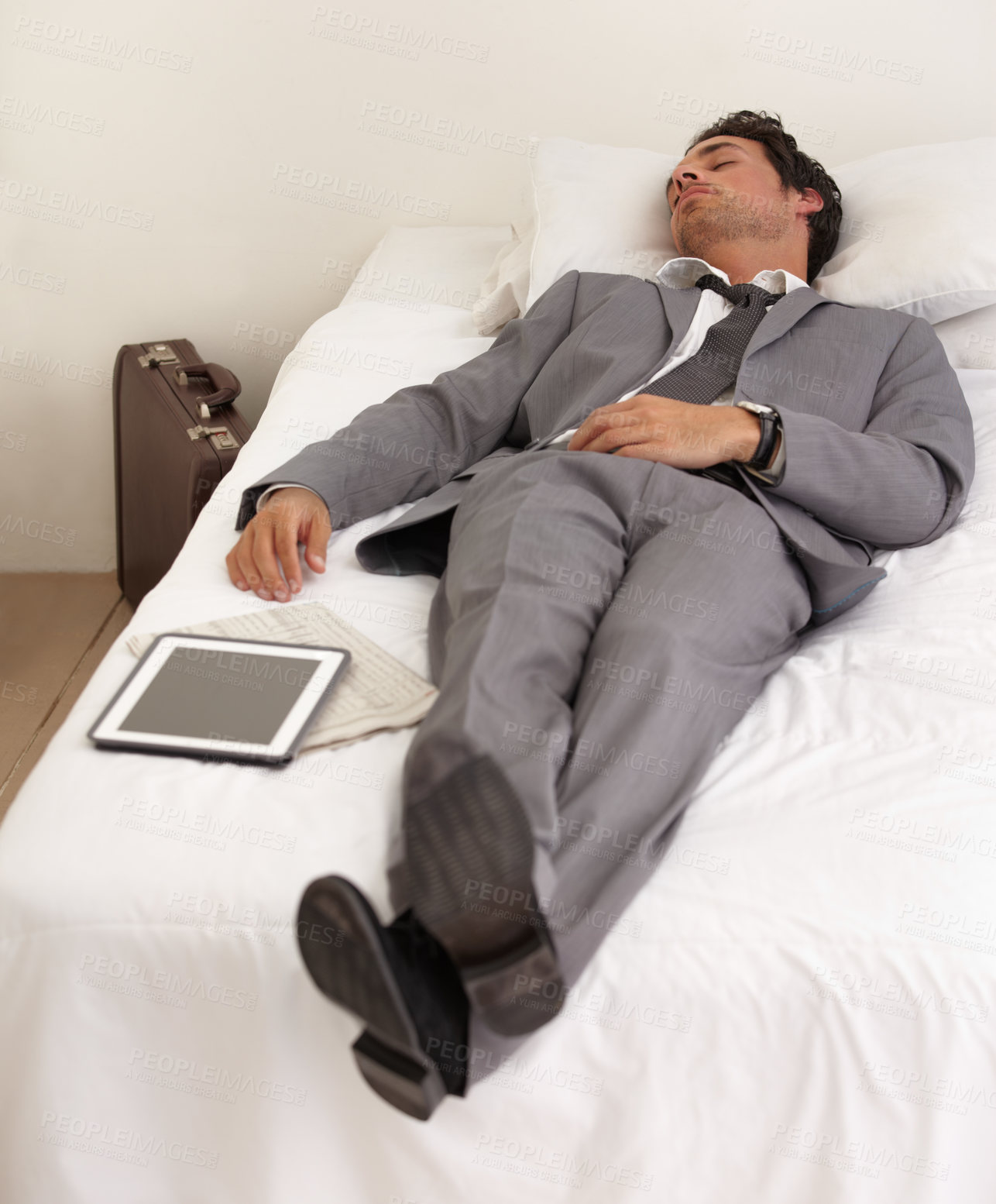 Buy stock photo A handsome young businessman sleeping on the bed with his digital tablet