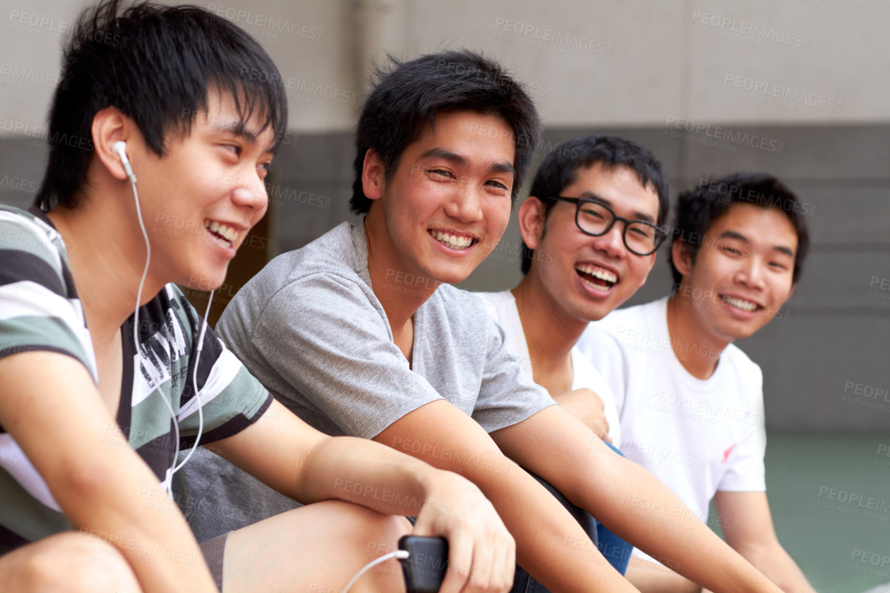 Buy stock photo Four young asian friends sitting in a row and smiling at the camera