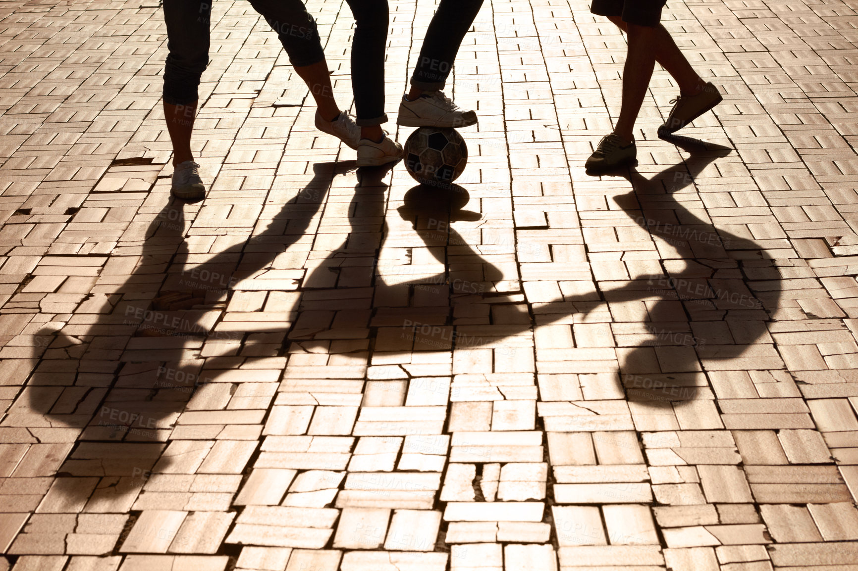 Buy stock photo Cropped image of legs kicking a ball with shadows on the paved road