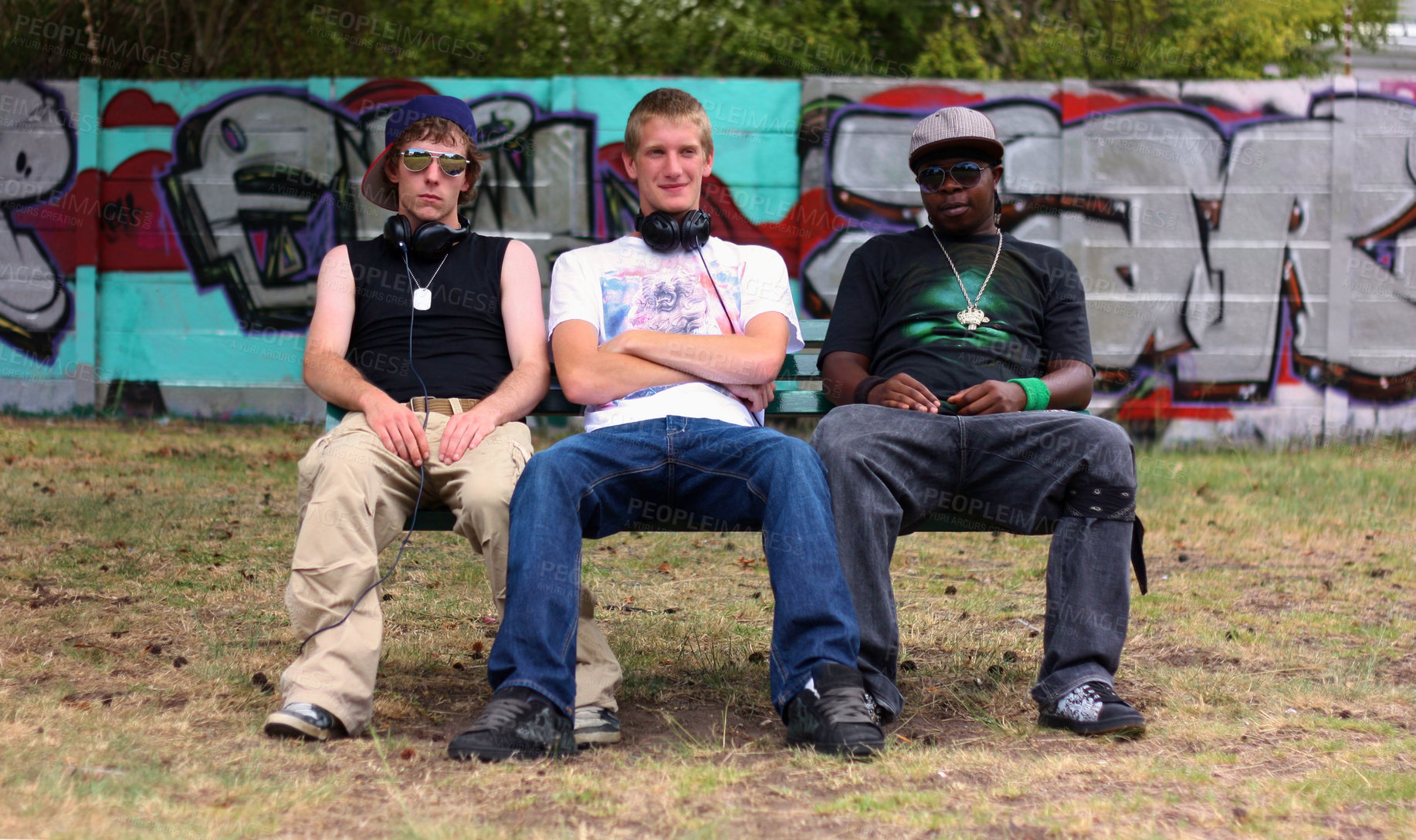 Buy stock photo Shot of a group of young urban teenagers sitting together on a bench outside