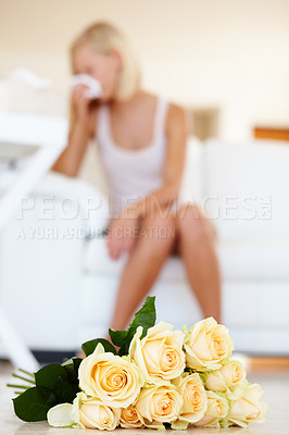 Buy stock photo A young woman sneezing in the background with roses lying on the floor