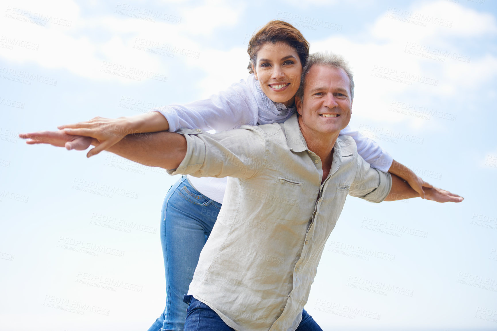 Buy stock photo Mature couple, portrait and piggy back on vacation, airplane hands and happiness in blue skies. Man, woman and bonding together with smile, marriage and commitment with affection, holiday and joyful
