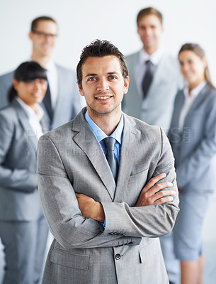 Buy stock photo Portrait of a handsome young businessman with his colleagues standing in the background