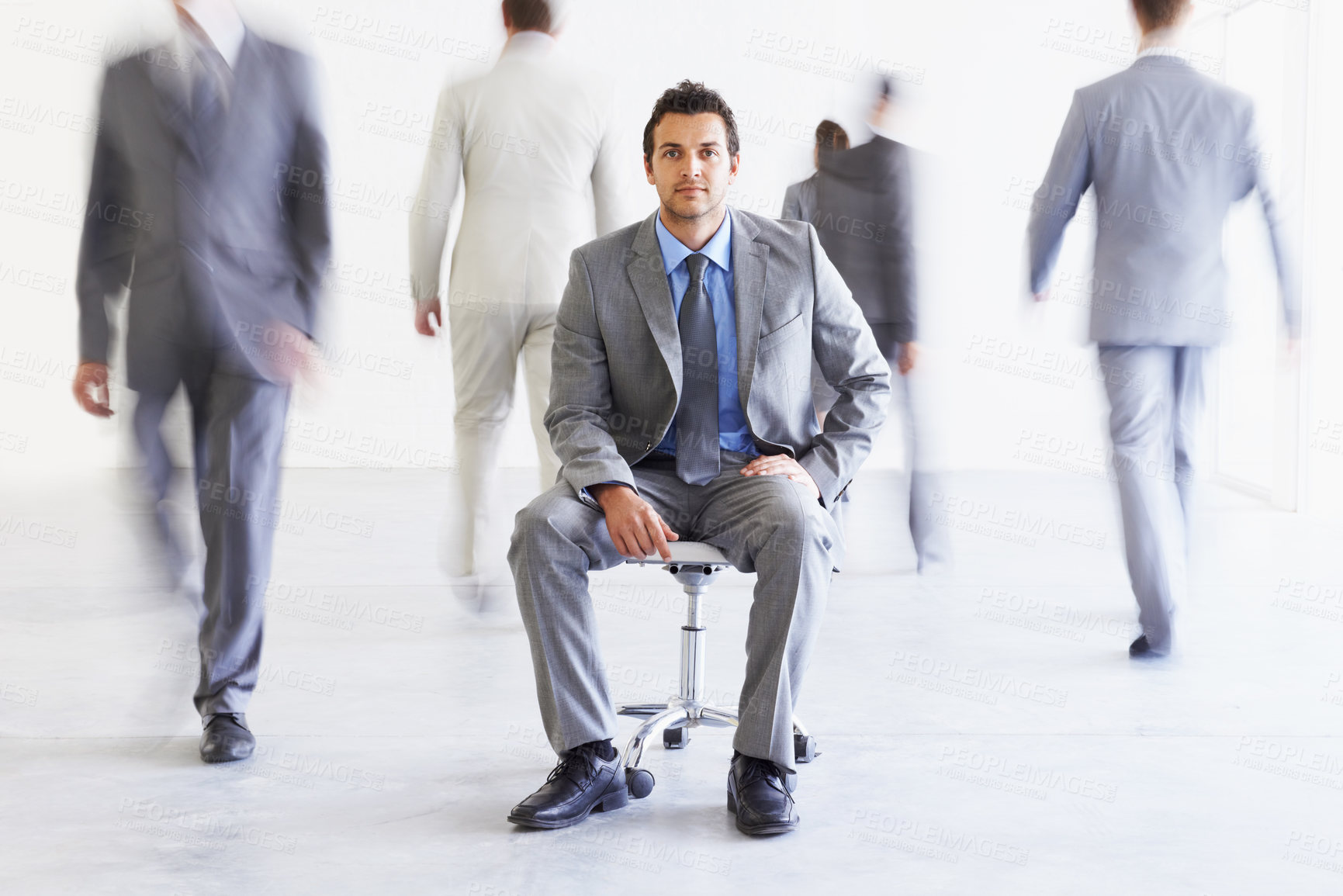 Buy stock photo Portrait, chair and a business man in a busy office with motion blur people walking for corporate productivity. Work, company and professional with a young employee in a suit sitting in the workplace