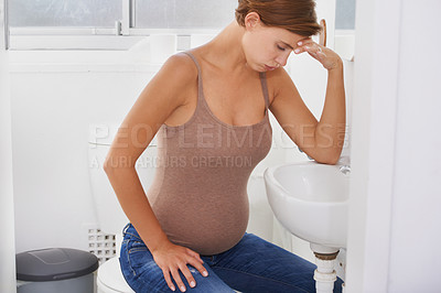Buy stock photo A pregnant woman struggling with morning sickness in the bathroom