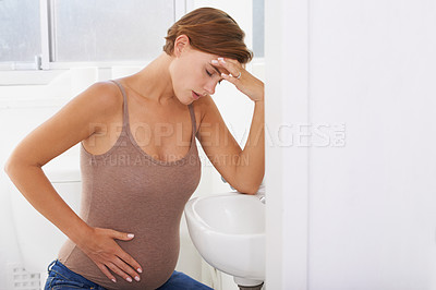 Buy stock photo A pregnant woman struggling with morning sickness in the bathroom