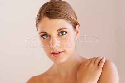 Buy stock photo Studio portrait of an attractive young woman with her hand on her shoulder smiling at the camera