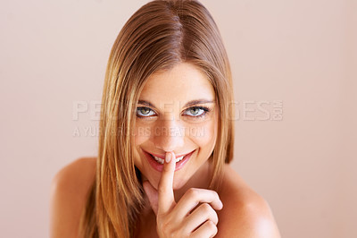 Buy stock photo Studio portrait of an attractive young woman making a 'shh' gesture at the camera